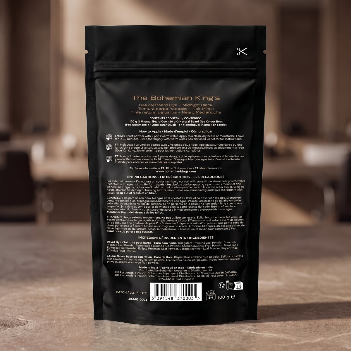 The back of a black resealable pouch for The Bohemian King's Natural Blend Roast Medium Coarse coffee, standing on a stone countertop with a blurred kitchen background.