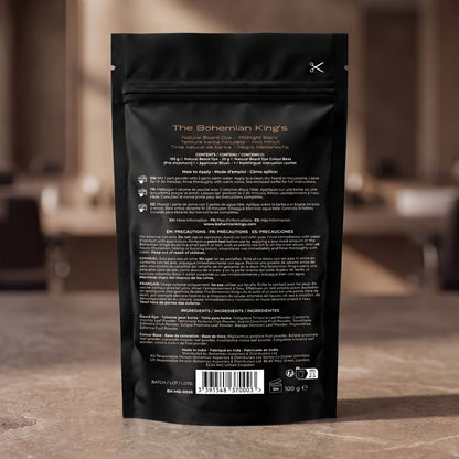 The back of a black resealable pouch for The Bohemian King's Natural Blend Roast Medium Coarse coffee, standing on a stone countertop with a blurred kitchen background.